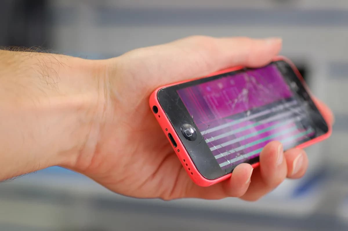 Phone whose display shows pink patches and horizontal lines — a damaged panel